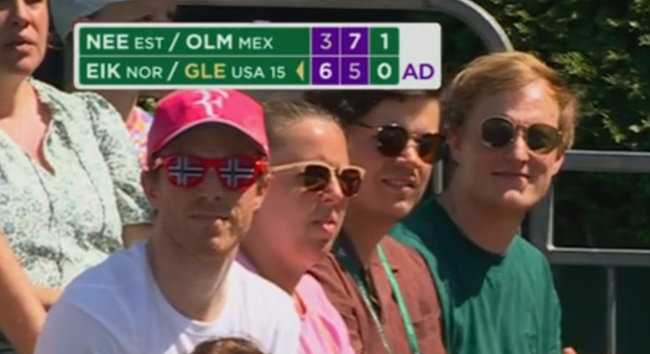 A photo of people in the crowd. The person on the left has some sunglasses that have the Norwegian flag printed on them.