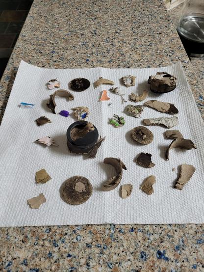 a paper towel littered with firework debris with a 40mm payload tube. Pieces that make up the end caps and side walls are present.