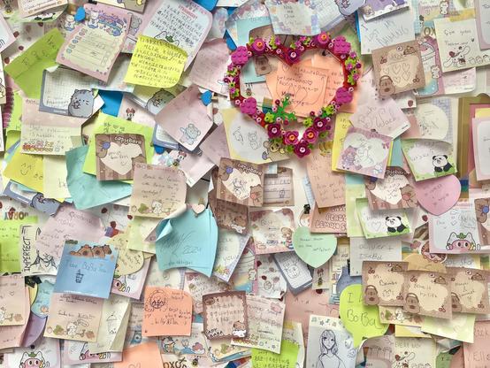 A cacophony of hundreds of cute girly post it notes on a wall, in many languages, about basically everything but especially bubble tea