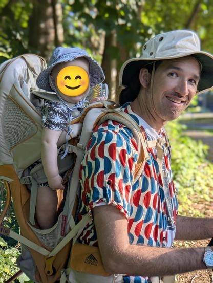 Baby in backpack with summer hat, just like Dad