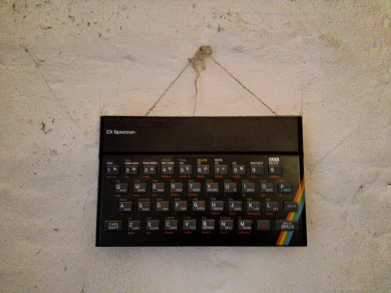 ZX Spectrum computer shell hanging on the wall from a tatty cord as decoration.