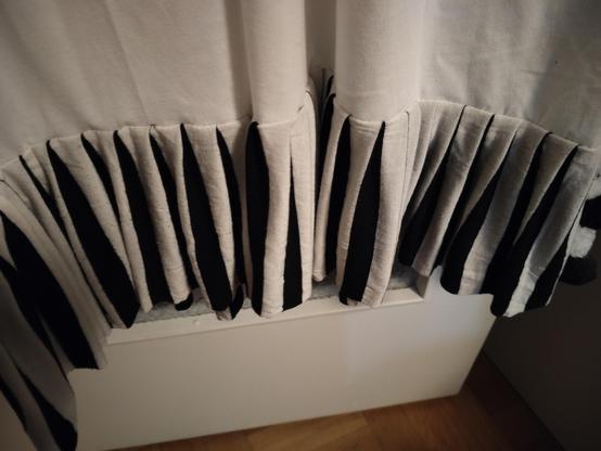 a close up of the bottom flounce, showing that it is made out of a striped fabric that has been folded so that the white stripes are at the front and the black stripes are at the back.