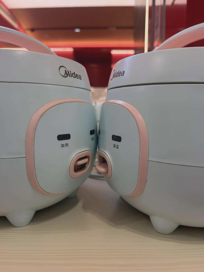 Two rice cookers standing next to each other, their control panels look like faces (the leds are the eyes, and the power switch is a tongue)
It looks like they're kissing.