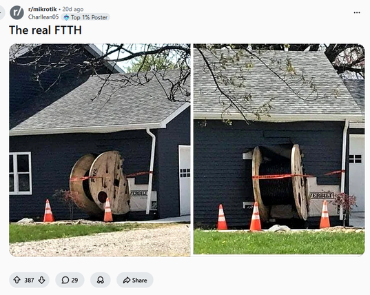 Two giant wooden fiber cable reels appear to have rolled into the side of a house. The caption says, "The real FTTH," joking about Fiber to the Home. The image itself is a screenshot from the MikroTik Reddit community.