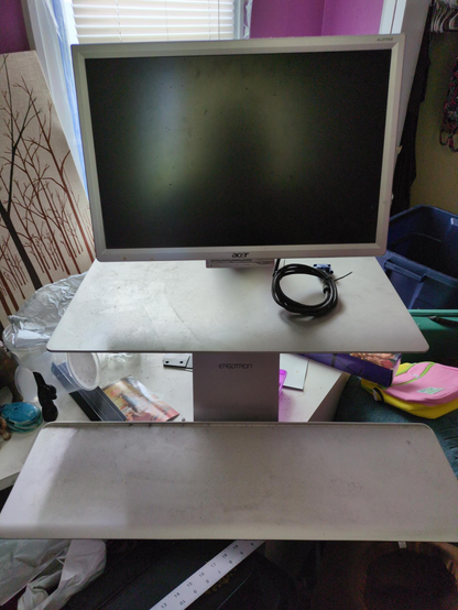 A dusty ergotron swingarm with a ancient VGA monitor attached seen directly on. It can easily hold a laptop, a NUC or mini PC.

Comes with keyboard tray.