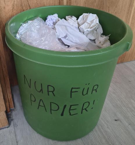 Ein Mülleimer mit großer Aufschrift „Nur für Papier