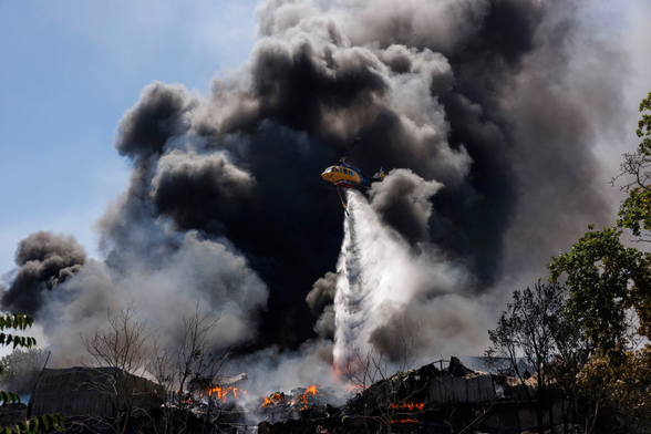 A firefighting helicopter drops water on a fire.