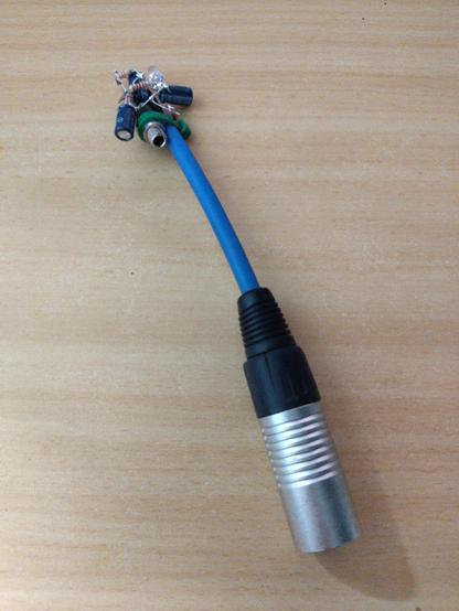 It's a mess of leads and components soldered together on the end of a microphone cable with an XLR plug. The jumble of components contains visiblu some capacitors, resistors, an LED and a 3.5mm socket.