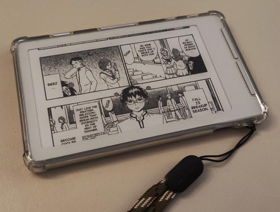 An xteink x4 ereader in a transparent tpu cover, lying on a flat surface. The screen is showing a page from a comic manga called Saiki Kusuo