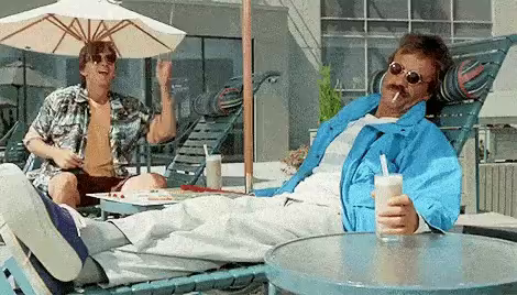 A clip from Weekend at Bernie's is shown, where a man wearing a hawaiian shirt is moving the arm of a dead Bernie using makeshift marionette strings.