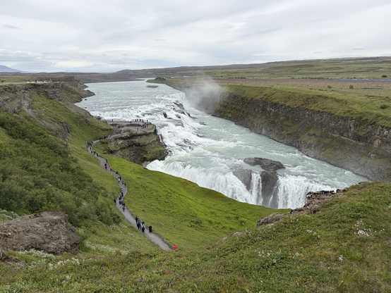 Giant waterfall surrounded by lush green land.