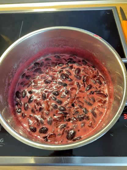 Red-pink fruit soup cooking in a pot. There's cherry pieces floating in it