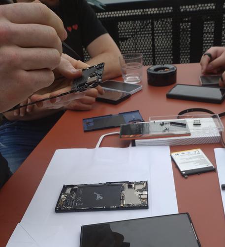 Das Telefon wird auf einem Tisch auseinandergebaut. Zu sehen ist der Body, eine demontierte Batterie, eine demontierte Kamera und jede Menge Schrauben.