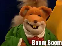 a stuffed animal is wearing a green jacket and a red bow tie and says boom boom