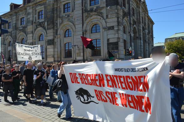 Demobild. Transparent im Vordergrund: Die Reichen enteignen bis sie weinen. Im Hintergrund: The only good general is the general strike.