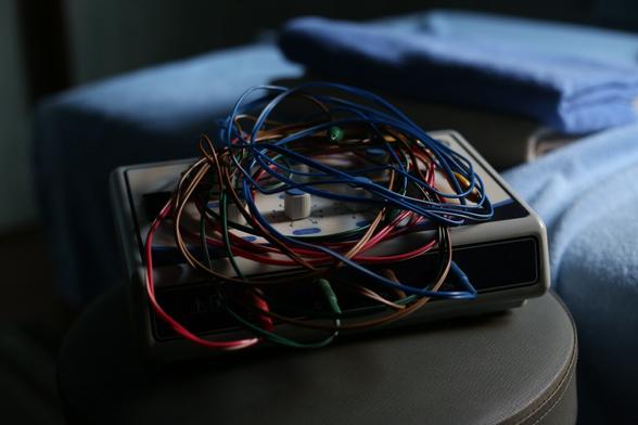 Medical equipment placed on a round, swivel chair.
Colorful cords are tangled around it.