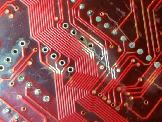 red circuit board with some bare coppery traces and soldered wires