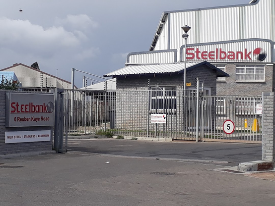 An industrial building behind a steel fence with signage that reads "Steelbbank."
