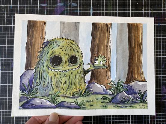 Strüppi wird von einem grasigen Waldmonsterchen gehalten. Sie sind im Wald. man seiht Baumstamme und Steine.