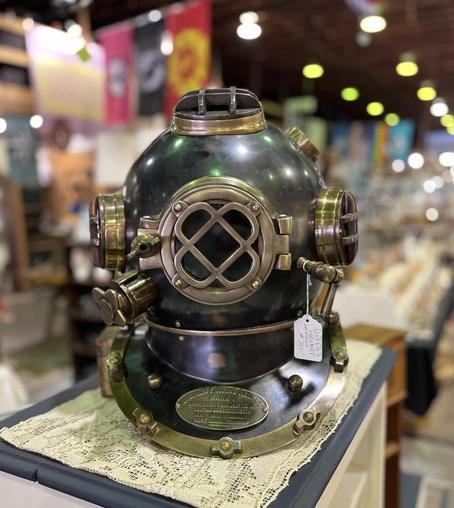 A picture taken in portrait style (somewhat blurred background) of an old US Navy diving helmet.