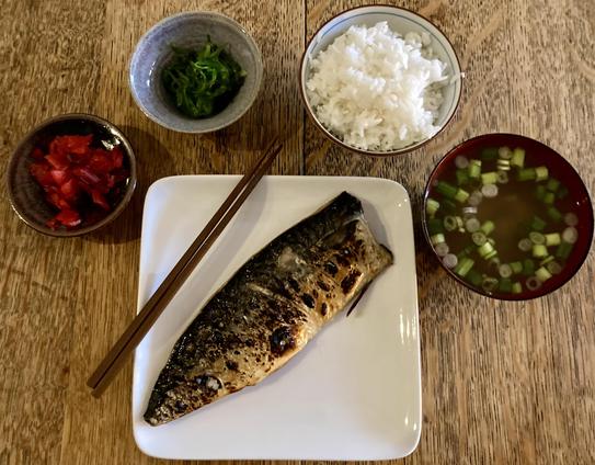 A Japanese-style dinner. Japanese pickles, seaweed salad, steamed rice, miso soup, and a broiled mackerel.