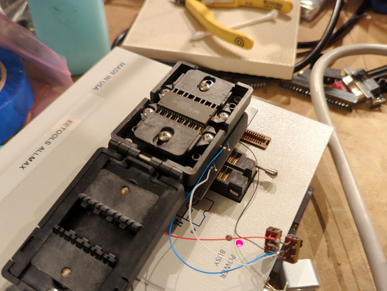 very large plastic socket with a 44-pin SOP part in it. the socket has adjustable guide combs to handle 0.05" pitch parts of various widths. it is plugged into an Allmax device programmer.
