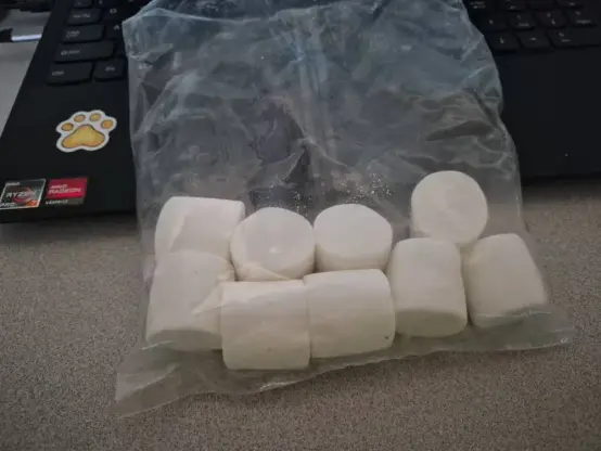 an unmarked bag of large marshmallows propped up against my laptop; you can see a paw sticker and amd ryzen/radeon stickers on the left side