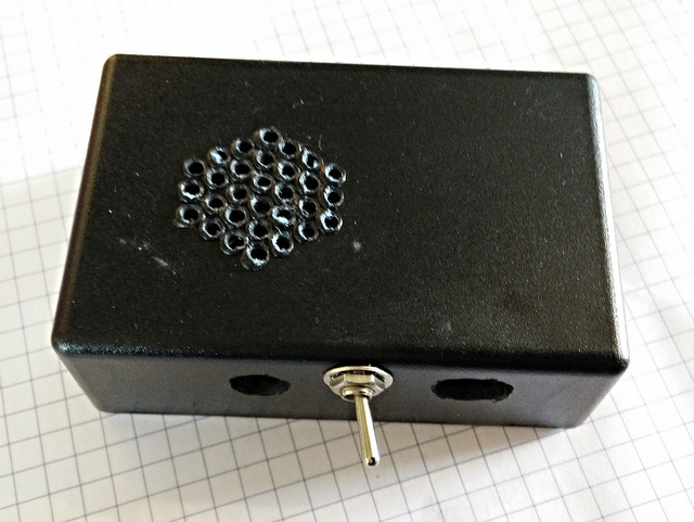 a small black component case with speaker holes, a switch and two sockets