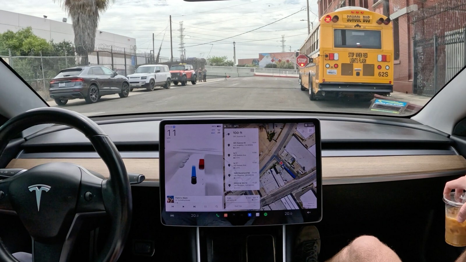 View from inside a self-driving 2018 Tesla Model 3 as it approaches a stopped school bus on a street in Los Angeles.