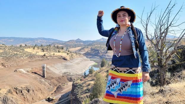 Brook Thompson stands above the Klamath River, with her fist raised (Credit: Brook Thompson)