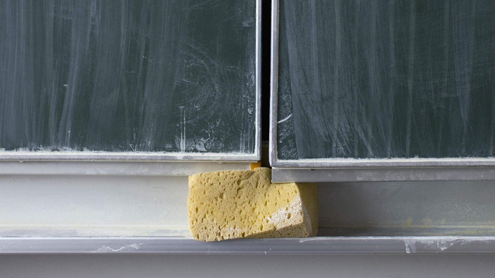 Schwamm, der unter einer Schultafel  eingeklemmt ist.