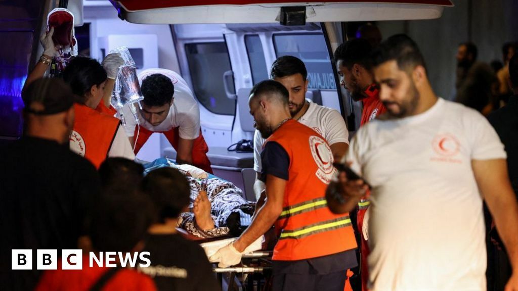 A wounded person is carried on a stretcher by medics from an ambulance in Beirut
