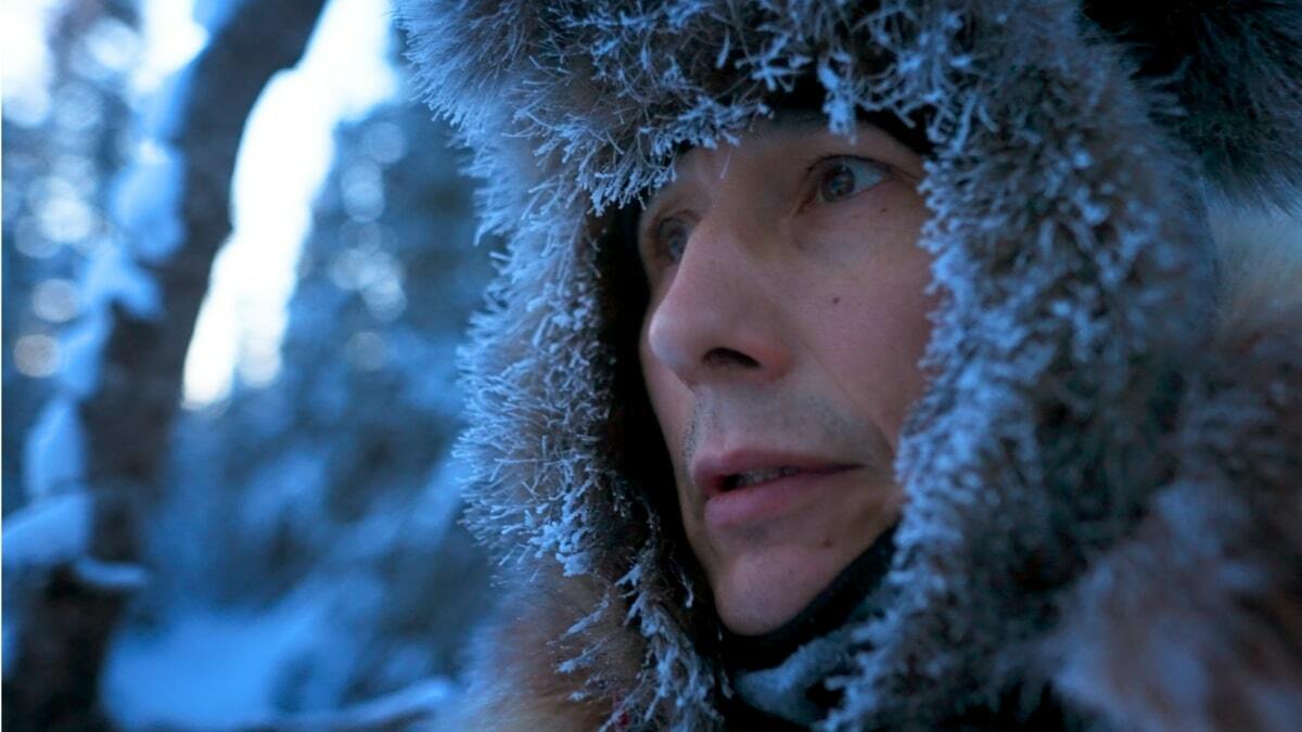 A person's face surrounded by an icy, furry hood
