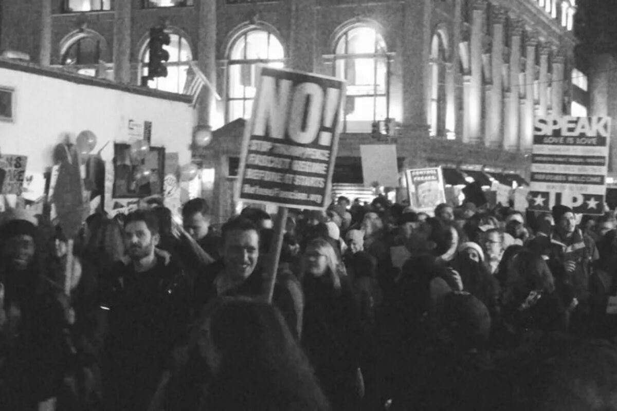 A black and white photo of a large crowd marching through the streets of Manhattan during the 2017 Women's March.