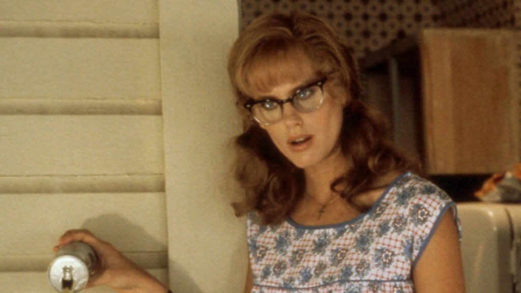 Daryl Hannah wears a retro southern smock and pours out a can of beer while standing on a porch in a still from 'Steel Magnolias'.