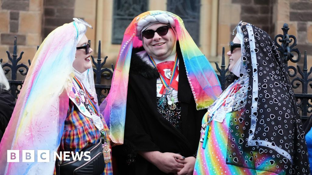 Three mourners dressed as colourful nuns, wearing rainbow habits and sunglasses and rainbow lanyards around their necks
