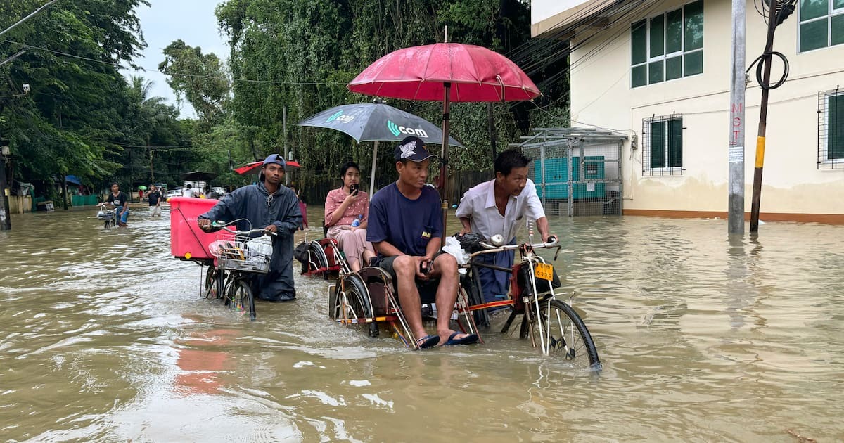 Trishaws und Fahrräder bahnen sich im Oktober 2024 ihren Weg durch eine nach heftigem Regen überflutete Straße in Myanmar.