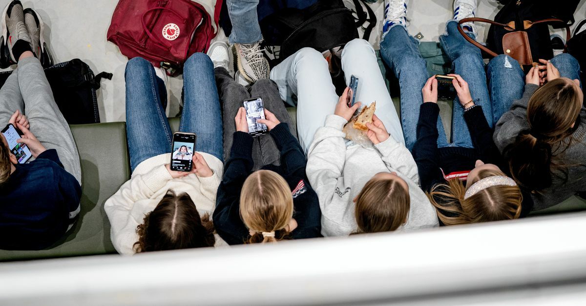 Scholieren kijken op hun smartphone, tijdens de pauze op het Leonardo College in Leiden 