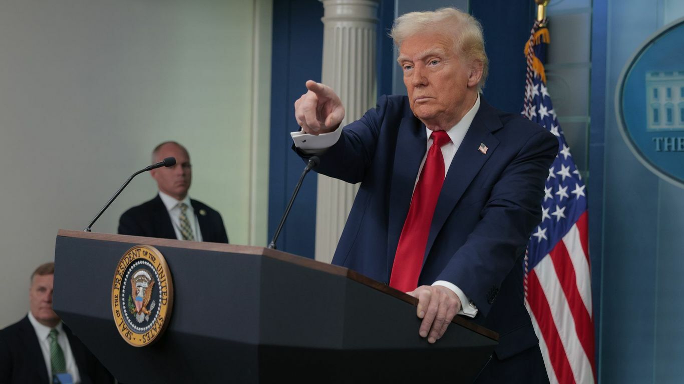 President Trump points at someone while standing behind a podium.