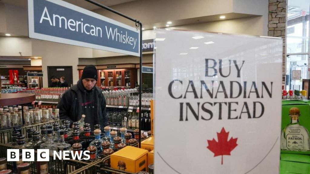 A customer holds a bottle as a sign that reads ''Buy Canadian Instead'' is displayed after the top five U.S. liquor brands were removed from sale at B.C. Liquor Stores, as part of a response to U.S. President Donald Trump's 25% tariffs on Canadian goods, in Vancouver, British Columbia, Canada, February 2, 2025.