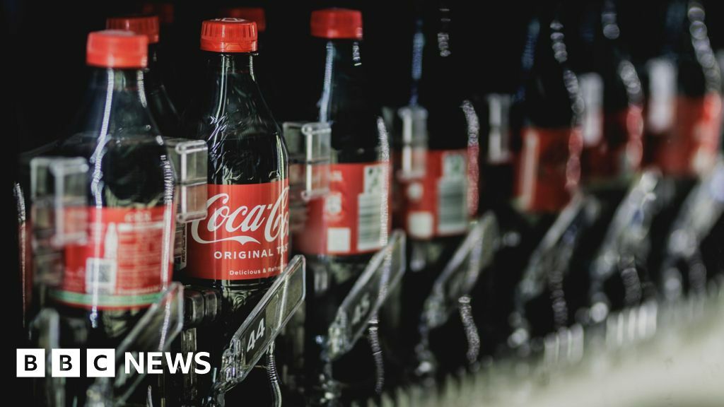 Bottles of Coca Cola pictured in a beverage dispenser.