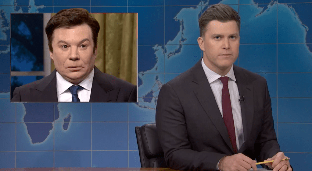 Colin Jost opposite an image of Mike Myers as Elon Musk on Weekend Update