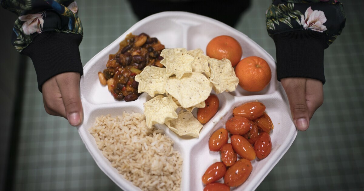 A seventh grader carries her plate which consists of three bean chili, rice, mandarins, cherry tomatoes and baked chips during her lunch break at a public school in the Brooklyn borough of New York on Friday, Feb. 10, 2023.
