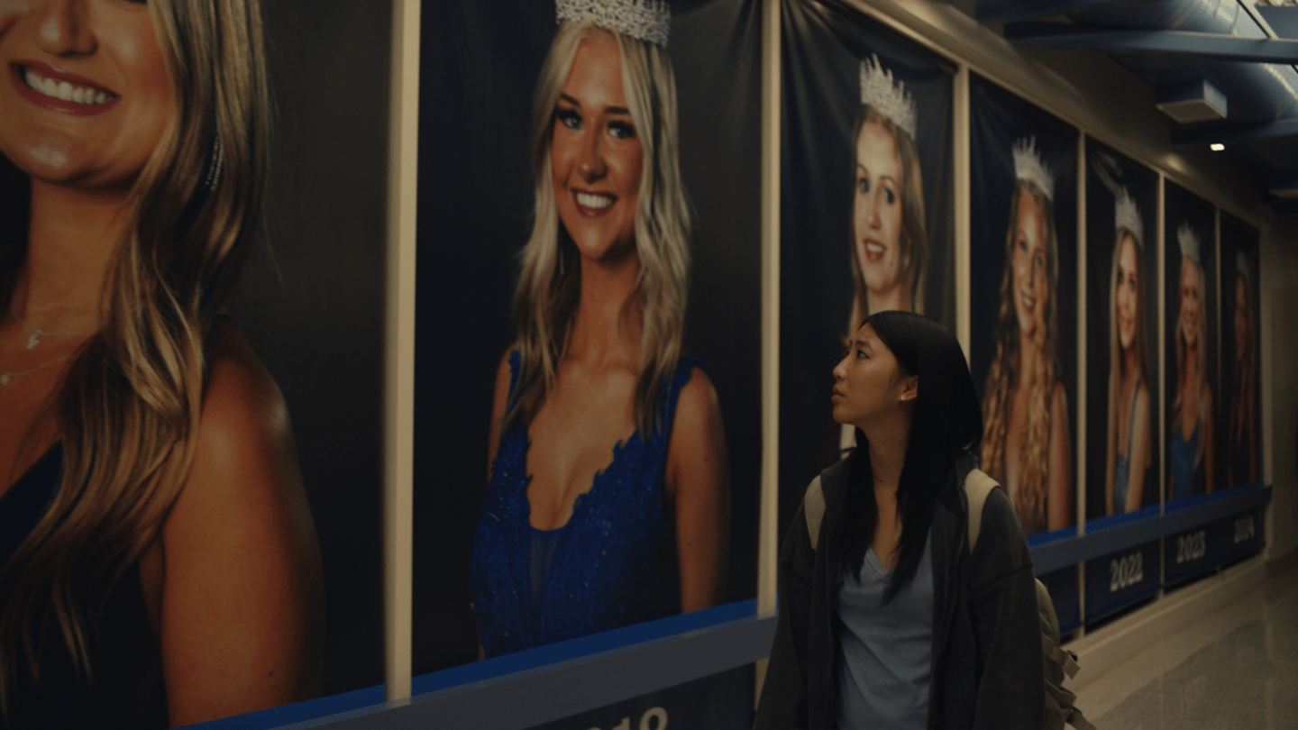 Shirley Chen, as Joan Huang in Amy Wang's SXSW feature Slanted, admires a series of portraits of white women in a hallway.