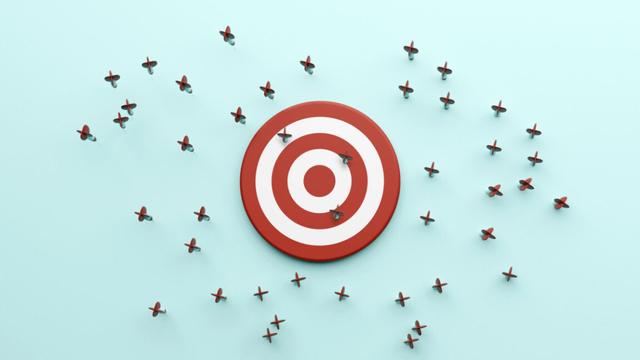 A dartboard with only a few darts hitting it, with many misses beside it.