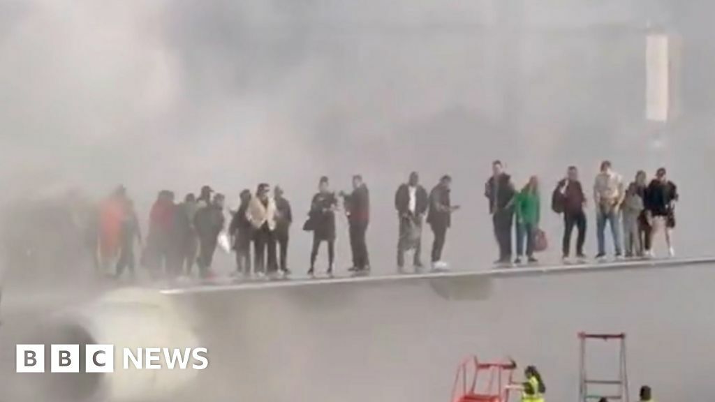 Passengers standing on the wing of a plane in thick smoke