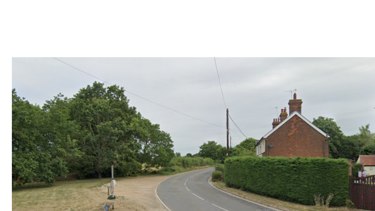 A street view image of Dedham Road. It is a country road with a house on one side and trees on the other.