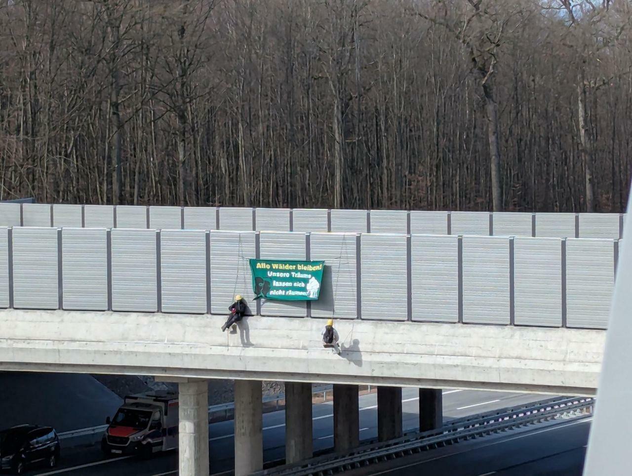 Menschen Seilen sich von wildbrücke mit Banner ab