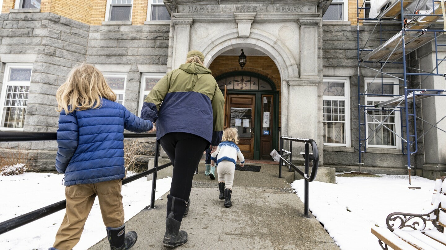 A family from the United States enters the Haskell Free Library and Opera House in Derby Line, Vt., on Friday, March 21, 2025. The town of Stanstead, Que., says U.S. authorities have unilaterally decided to "close the main Canadian access" to the Victorian-style library that straddles the border between the two countries. (Christinne Muschi/The Canadian Press via AP)