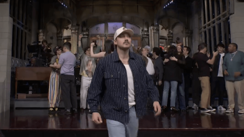 Morgan Wallen walks off the 'Saturday Night Live' set as the cast celebrates behind him.